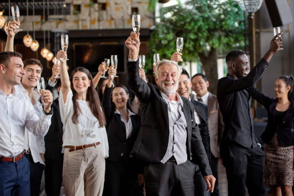 Arbeitskollegen heben Champagnergläser in die Luft