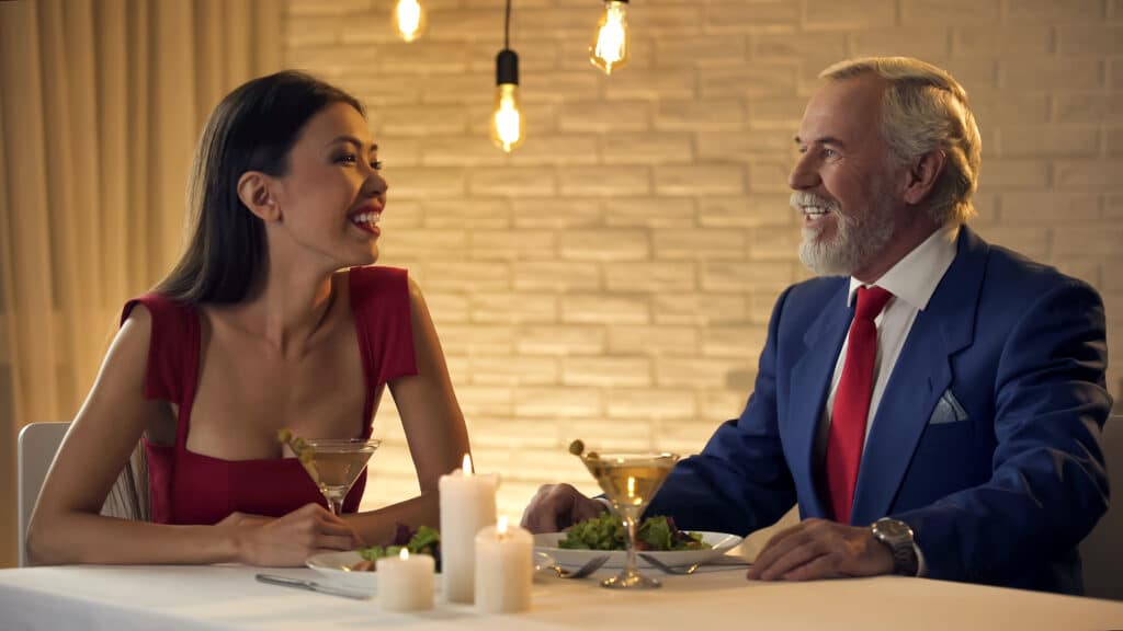 Junge Frau und aelterer Herr beim stilvollen Abendessen – typische Szene fuer professionelle Begleitung im Kontext von Escort werden