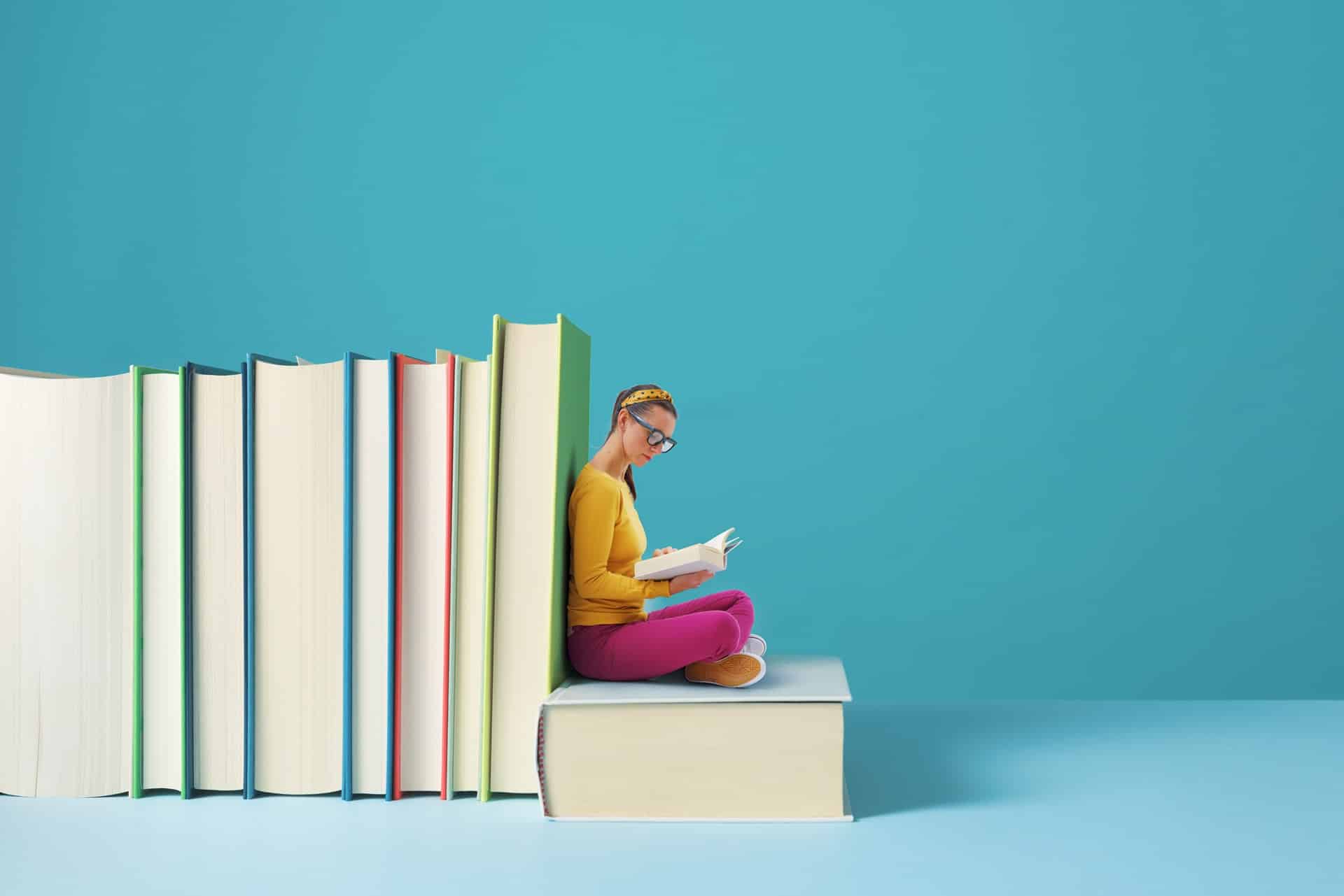 Frau liest inmitten großer Bücher | E-Learning Anbieter